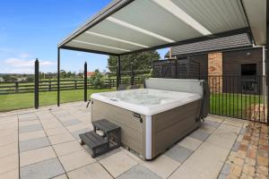 a hot tub in a patio with a roof at Airport Oasis in Rotorua
