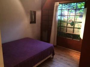1 dormitorio con cama morada y ventana en La Escondida - Casa Quinta en los Cardales en Los Cardales