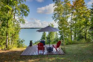 una terraza de madera con 2 sillas y una sombrilla en Lakefront Paradise with Private Boat Dock and Patio, en Deer River