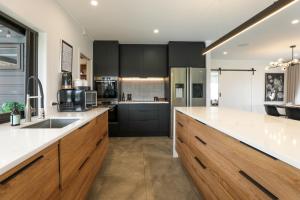 a kitchen with black cabinets and white counter tops at Airport Oasis in Rotorua