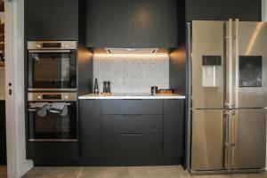 a kitchen with black cabinets and a stainless steel refrigerator at Airport Oasis in Rotorua
