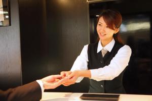 una mujer le da la mano a un hombre en Hotel Chatelet Inn Kyoto, en Kioto