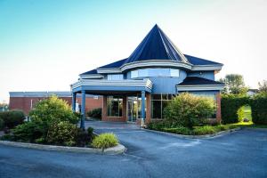 un grand bâtiment avec un toit en gambrel dans l'établissement Hôtel Val-des-Sources, à Asbestos