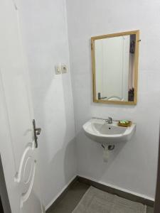 La salle de bains blanche est pourvue d'un lavabo et d'un miroir. dans l'établissement STUDIO TIARÉ DIEGO, à Antsakomboena
