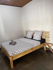- un lit en bois avec 2 oreillers dans l'établissement STUDIO TIARÉ DIEGO, à Antsakomboena