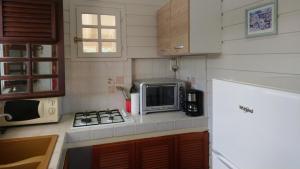 a small kitchen with a microwave and a stove at Zénitude Bungalow in Le Lorrain
