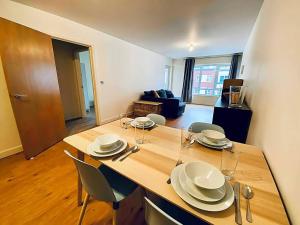 a dining table with plates and glasses on it in a living room at Secure 2BR 1BA Apartment for 6 in Colindale