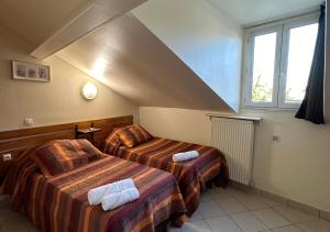 a hotel room with two beds and a window at Hôtel Victor Hugo in Aubervilliers