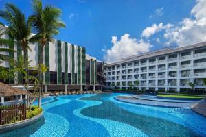 a hotel with a swimming pool in front of two buildings at The Stones Hotel - Legian Bali, Autograph Collection in Kuta