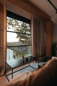 ein Wohnzimmer mit einem Tisch und einem großen Fenster in der Unterkunft Calm House Villa in Prijedor