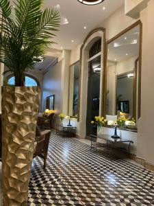 a hotel lobby with a palm tree in a large vase at Boutique Hotel Belgica in Ponce