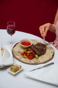 une personne coupant un steak avec une fourchette et un couteau dans l'établissement Radisson Hotel Astana, à Astana