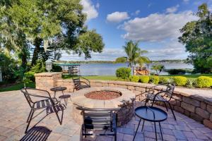 a patio with chairs and a fire pit with a view of the water at Lakefront Winter Haven Retreat Hot Tub and Patio! in Winter Haven