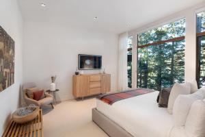 1 dormitorio con 1 cama, TV y ventanas en Kadenwood 2927 - Luxury Mountain View Chalet, Jacuzzi, Media Room - Whistler Platinum en Whistler