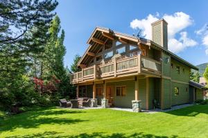 a large house with a balcony and a yard at Meadow Green Chalet - Family Chalet, Golf Course, Hot Tub, BBQ, Garden - Whistler Platinum in Whistler