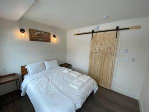 エドモントンにあるLovely 1 Bedroom Condo Free Parking And Balconyの白いベッドと木製のドアが備わるベッドルーム1室が備わります。