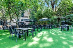 un groupe de tables et de chaises avec parasols dans l'établissement Doubletree By Hilton London Kensington, à Londres