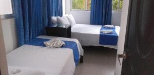 a hotel room with two beds and blue curtains at Tropical Resort Tocaima in Tocaima