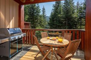 a wooden deck with a table and chairs and a stove at Taluswood The Lookout 5 - Secluded Chalet with Hot Tub & Incredible Views - Whistler Platinum in Whistler