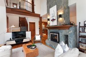 a living room with a large stone fireplace at Taluswood The Lookout 5 - Secluded Chalet with Hot Tub & Incredible Views - Whistler Platinum in Whistler