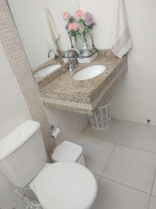 a bathroom with a white toilet and a sink at Casa de Praia Balneário Piçarras in Piçarras