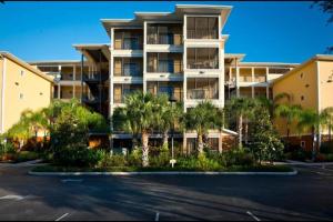 een appartementencomplex met palmbomen op een parkeerplaats bij 9055 Resort Gem Condo-3 bed/2ba in Kissimmee