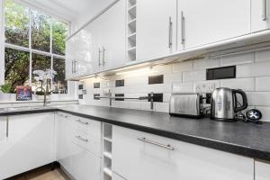 a kitchen with white cabinets and a counter top at Maida Vale, Central Modern Apt, Sleeps 4, London. in London