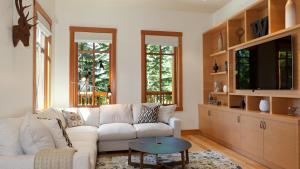 uma sala de estar com um sofá branco e uma televisão em Kadenwood 2972 - Mountain Chalet, w/ Hot Tub, Pool Table, Fireplace - Whistler Platinum em Whistler
