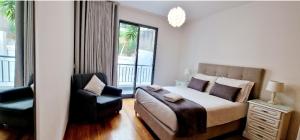 um quarto com uma cama, uma cadeira e uma janela em Ocean Pearl Apartment K em Funchal