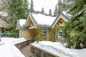 a house covered in snow in the woods at Snowbird 304 - Beautiful Townhome with Hot Tub & Secure Parking - Whistler Platinum in Whistler