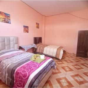 2 camas en una habitación con paredes rosas en Como en casa, en Sucre