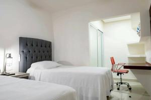 a white bedroom with two beds and a chair at Luxury and Comfort in the heart of Vallarta in Puerto Vallarta +18 photos