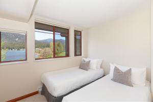 two beds in a white room with windows at Lakeside Landing - Lake & Golf Course Views from Private Balcony - Whistler Platinum in Whistler