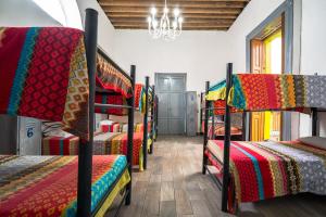 Habitación con varias literas y mantas coloridas. en Hostal Santo Domingo, en Puebla