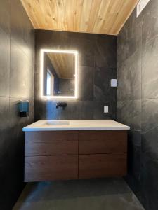 La salle de bains est pourvue d'un lavabo et d'un miroir. dans l'établissement Magical Loft : Breathtaking View & Cozy Fireplace, à Saguenay