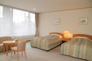 神戸市にある有馬 瑞宝園のベッド2台、テーブルと椅子が備わるホテルルームです。