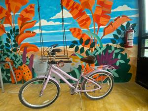 LUX Studio ROOM LAS PALMAS PUERTO MORELOS في بويرتو موريلوس: دراجة وردية متوقفة أمام لوحة جدارية