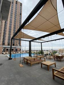 a patio with wooden benches and a large umbrella at Lux 2 bedroom apartment, swimming pool, gym and free parking spot in Macro Plaza area in Monterrey