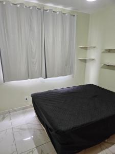 um quarto com uma cama e uma janela com cortinas brancas em Apartamento Cabo Frio Maciel em Cabo Frio