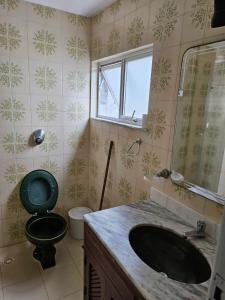 uma casa de banho com um WC verde e um lavatório em Apartamento Cabo Frio Maciel em Cabo Frio