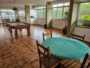 Habitación con mesa de ping pong y sillas. en Apartamento Cabo Frio Maciel, en Cabo Frío