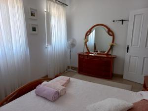 a bedroom with a bed with two towels and a mirror at A Casa da Avó Ana in Arneiro das Milhariças