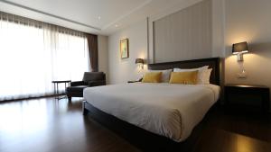 una camera d'albergo con un grande letto e una sedia di The Dawin Hotel a Bangkok