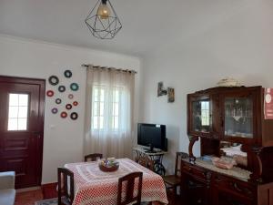 uma sala de estar com uma mesa e uma televisão em A Casa da Avó Ana em Arneiro das Milhariças