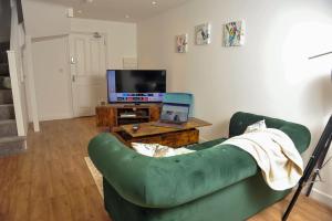 a living room with a green couch and a television at Select SA - Queens Terrace in Reading