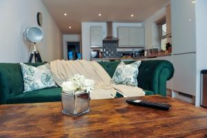 a living room with a green couch and a table with a remote control at Select SA - Queens Terrace in Reading