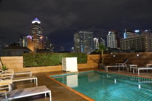 a swimming pool with a view of the city at night at The Dawin Hotel in Bangkok