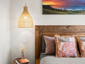 een slaapkamer met een bed met een houten hoofdeinde bij THE PENTHOUSE - Spectacular Views of the Bay, and the Ocean! Only 150m to Shaws Bay in East Ballina