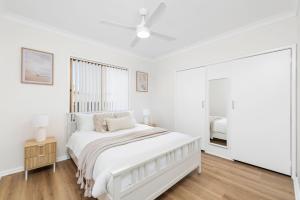 biała sypialnia z łóżkiem i oknem w obiekcie 2A Rigney Street Shoal Bay w mieście Shoal Bay