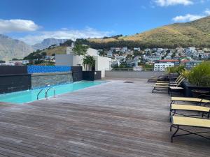 a rooftop deck with a swimming pool and mountains at Cape Royale Luxury Suite in Cape Town